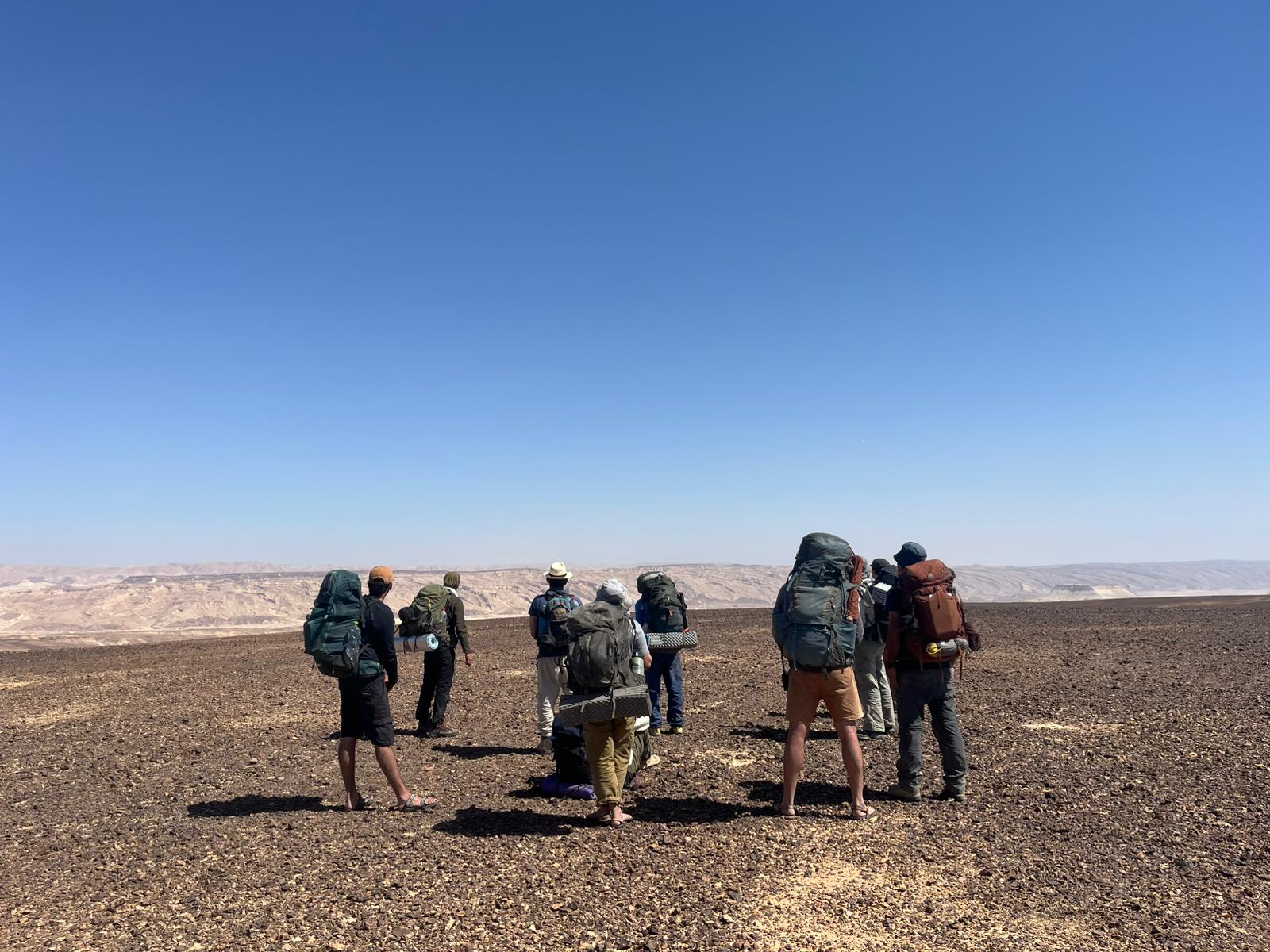 קבוצת מטיילים עם תרמילים עומדת ומביטה אל המרחב המדברי הפתוח